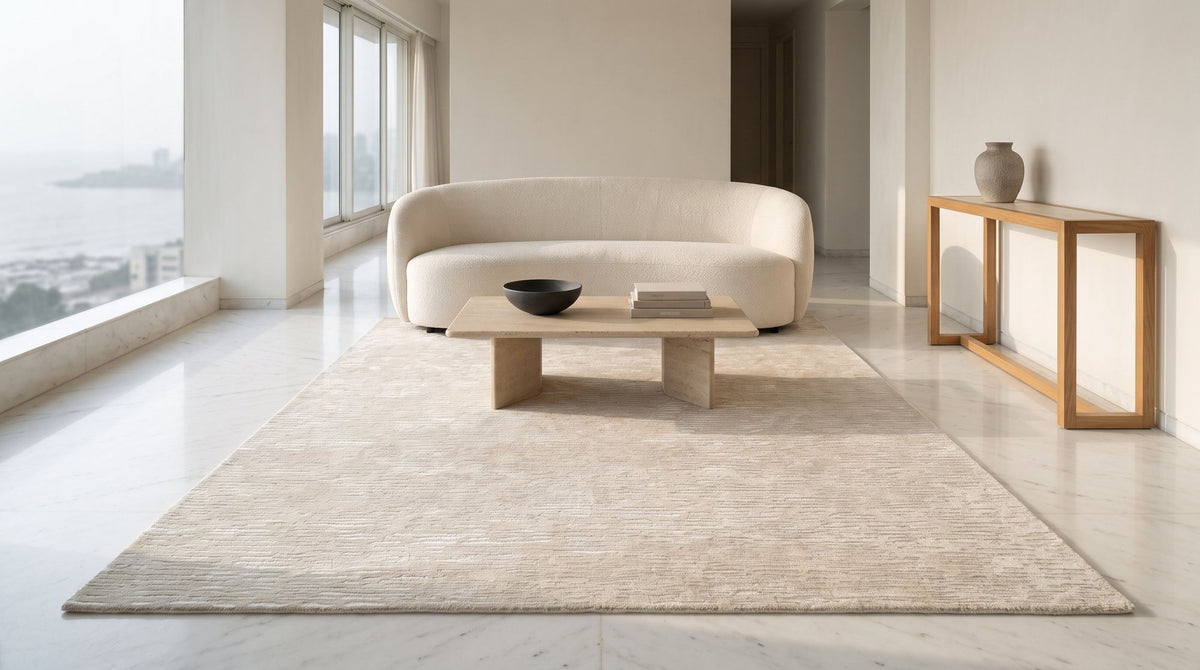 Cabella Wool & Silk Rug in Frost in a sea view living room, a pale hand tufted wool and silk rug on a marble floor. A companion to Fragment, shown while Fragment awaits real photography.