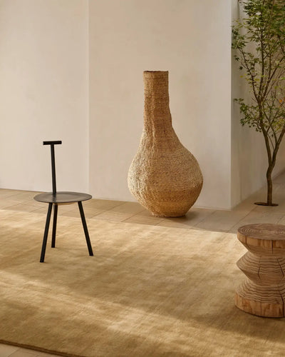 A Rugberry rug in a sunlit room with a woven floor vase and a low wooden stool